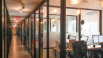 Corridor of offices separated by glass with black metal frames